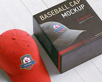 Red baseball cap with logo next to a black box labeled 'Baseball Cap Mockup' on a light wooden surface.
